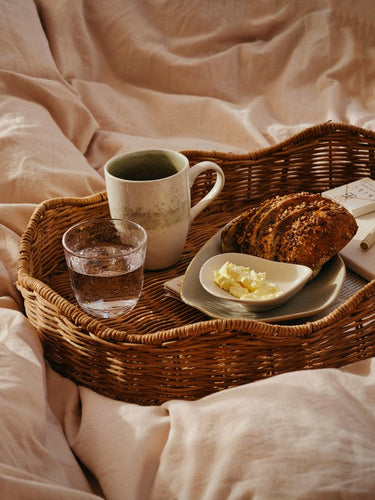 Bandeja de ratán con desayuno sobre una cama
