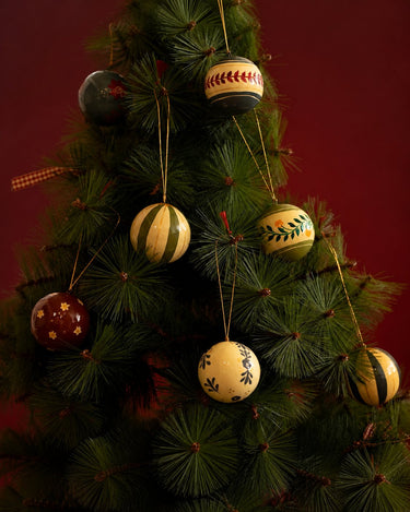 Bolas de Navidad de Mahe Homeware de varios colores colgadas en el árbol.
