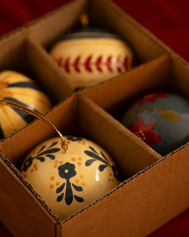 Juego de cuatro bolas navideñas azules y crema colocado en su caja.
