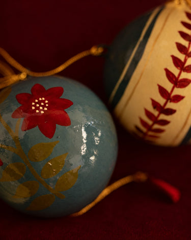 Bolas de Navidad de papel maché: detalle de una flor pintada sobre fondo azul.