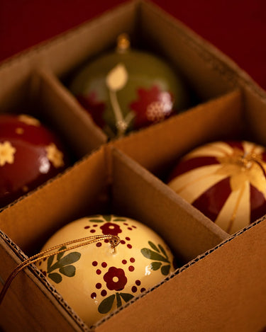 Bolas de Navidad de Mahe Homeware, juego de cuatro adornos pintados a mano en su caja.