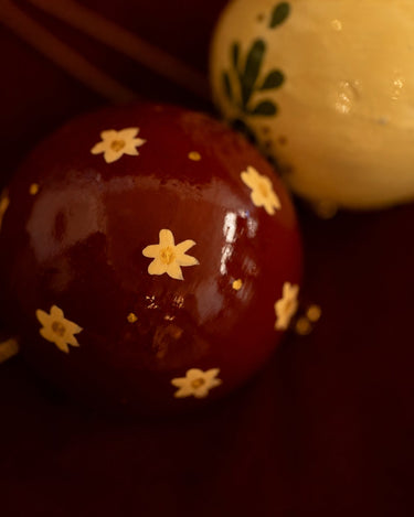 Bolas de Navidad de papel maché: detalle de los motivos claros sobre fondo rojo.