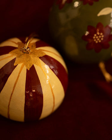 Detalle de una bola de papel maché con franjas rojas y crema.