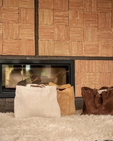 Bolso grande de pana color canela, bolsos en tonos claros y marrones junto a una chimenea