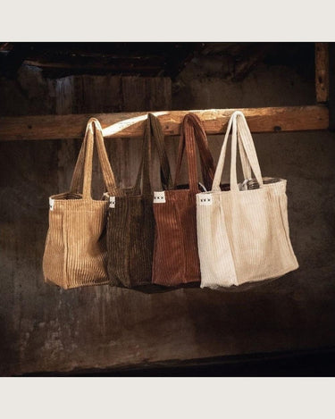 Bolso grande de pana color canela, bolsos marrones y claros colgados juntos