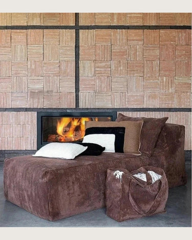 Bolso grande de pana color canela, junto a un sofá marrón y una chimenea