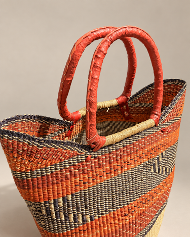 Bolso shopper de Matuta Home visto en ángulo, con dos asas rojo coral y trenzado geométrico