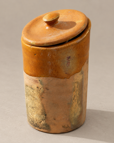 Bote de barro antiguo con tapa sobre fondo topo claro
