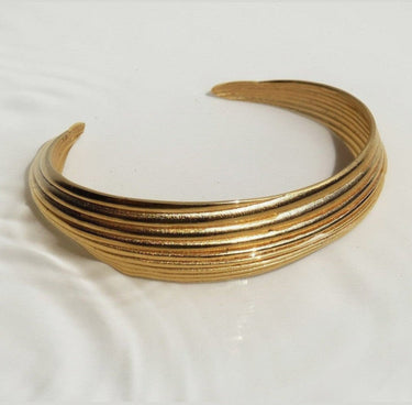 Brazalete abierto Onaria dorado de Carme Fàbregas de Joidart, detalle de las líneas curvas sobre tela clara