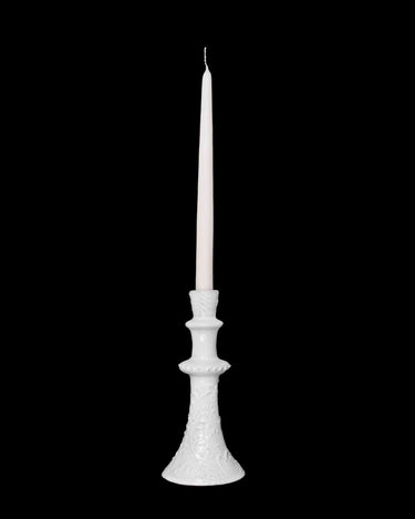 Candelabro alto con vela blanca, aislado sobre fondo negro.