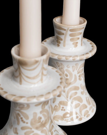 Detalle de dos candelabros blancos y beige, con motivos de trazos cortos y líneas curvas