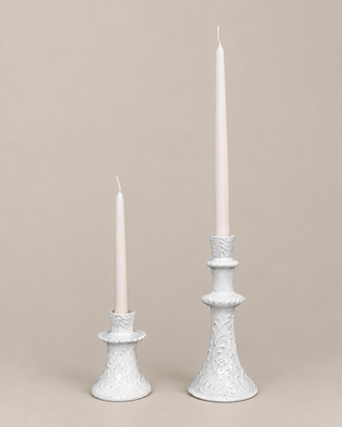 Candelabros artesanales de Leandro Cano, alto bajo con velas, sobre fondo topo claro.