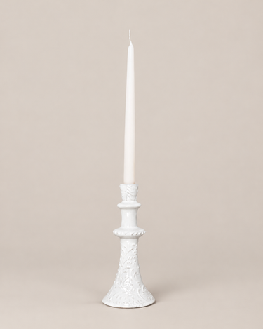 Candelabros artesanales de Leandro Cano, alto con vela, sobre fondo topo claro.