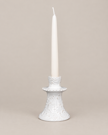 Candelabros artesanales de Leandro Cano, bajo con vela, sobre fondo topo claro.