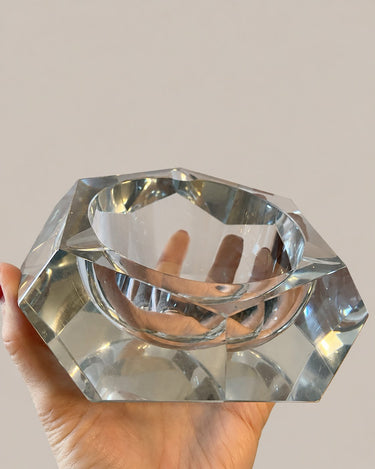 Cenicero vintage de cristal transparente sostenido en la mano, vista superior oblicua