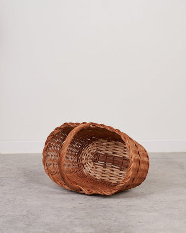 Cesta ovalada de mimbre con asa reforzada de Cestería Aparici, tumbada, con el interior visible