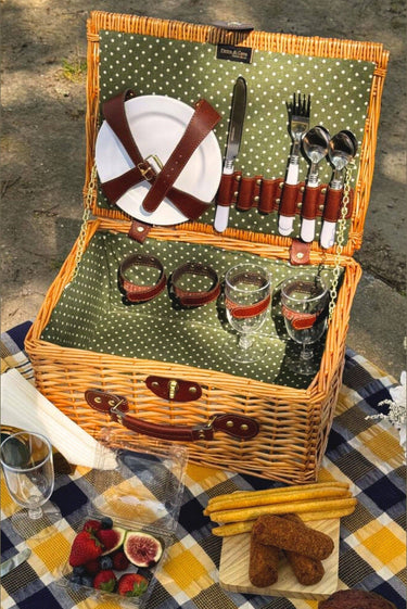 Cesta de picnic de mimbre natural para cuatro personas de PIETRA DI CASA, abierta sobre un mantel de cuadros