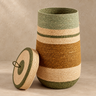 Green and hazelnut seagrass laundry basket with lid on a light taupe background
