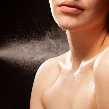Pulverización de una bruma sobre el cuello y el escote de una modelo.