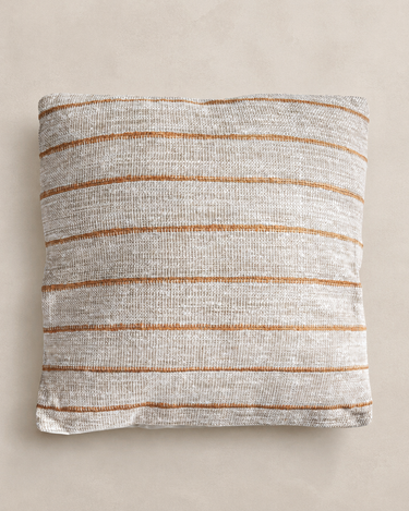 Cojín de algodón y lino beige terracota de Vical ante pared texturizada topo claro