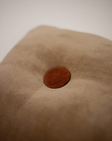 Beige buttoned decorative cushion by Olsson & Jensen on a sofa