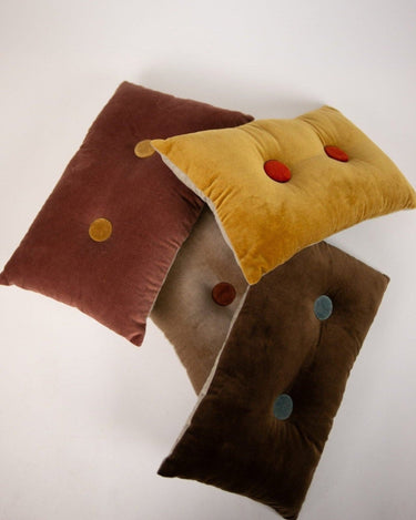 Brown buttoned decorative cushion by Olsson & Jensen on a sofa