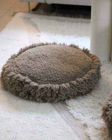 Detalle del tufting artesanal de un cojín de suelo redondo de algodón marrón
