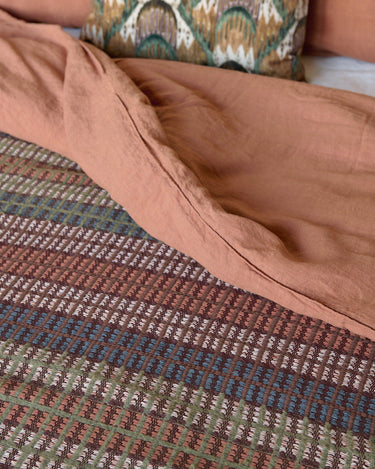 Colchas y textiles de cuadros en tonos tierra sobre una cama