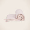 Colcha de lino lavado rosa con rayas y pompones de Caravane, enrollada