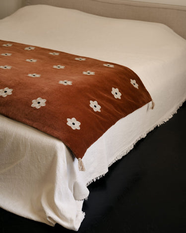 Colchoneta Daisy óxido plegada sobre una cama de dormitorio