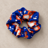 Coletero reciclado azul y naranja de House of Scrunchies, en poliéster, sobre fondo topo claro