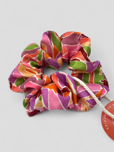 Detalle de uno de los coleteros de House of Scrunchies: estampado abstracto en rosa, verde, naranja y morado