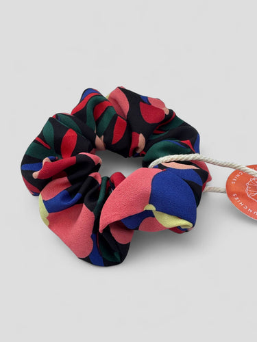 Detalle de uno de los coleteros de House of Scrunchies: flores coral y azul sobre fondo oscuro