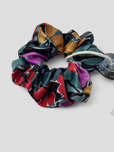 Detalle de uno de los coleteros de House of Scrunchies: flores grandes multicolor sobre fondo oscuro