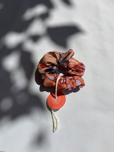 Coletero de House of Scrunchies: coletero apoyado junto a sombras de plantas, modelo de flores retro en tonos tierra