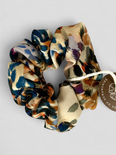 Detalle de uno de los coleteros de House of Scrunchies: estampado de leopardo multicolor y pliegues del tejido