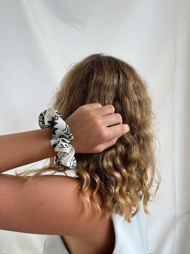 Coletero de House of Scrunchies: coletero en la muñeca junto al cabello rizado, modelo ornamental verde oliva y blanco