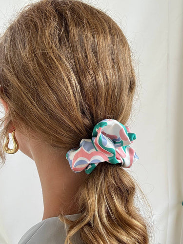 Uno de los coleteros de House of Scrunchies, de satén azul, rosa y verde, en una coleta vista de lado