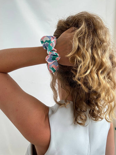 Coletero de House of Scrunchies: coletero en la muñeca junto al cabello rizado, modelo de satén reciclado azul, rosa y verde
