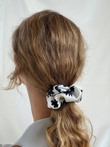 Coletero de House of Scrunchies: detalle del coletero en una coleta, modelo de satén reciclado con flores negras