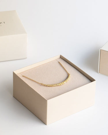 Un collar dorado de bolitas dentro de caja clara.