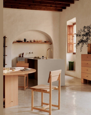 Cajonera parcialmente visible a la derecha de un comedor con silla y mesa de madera.