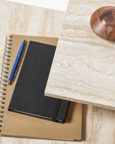 Detalle con cuadernos, bolígrafo y cuenco de madera.