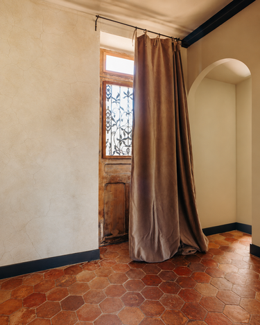 Cortina de terciopelo de algodón con forro de lino en topo de Le Monde Sauvage, cortina color topo junto a una ventana de madera