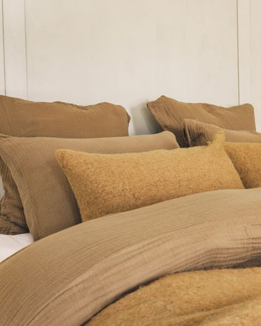 Cojin lana jaspeado miel en cama con plaid