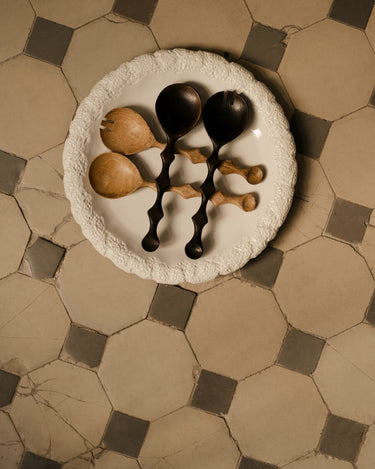 Cubiertos para ensalada en madera oscura y natural sobre una fuente