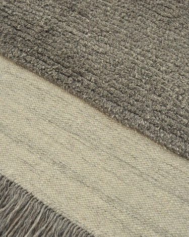 Detalle de alfombra de lana tono piedra Humble Act Linie Design con diseño geométrico discreto