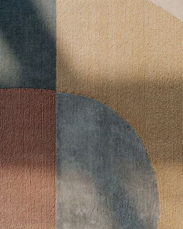 Detalle de alfombra redonda de lana bicolor con diseño solar seráfico Seraphic Sun Linie Design