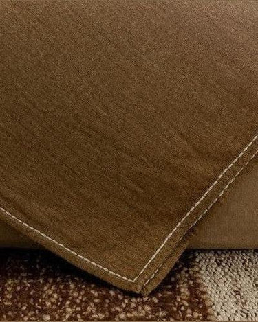 Detalle de un plaid degradado oliva y marrón sobre un asiento