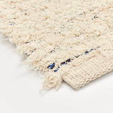 Detalle del tejido y los flecos de la alfombra de algodón blanco roto